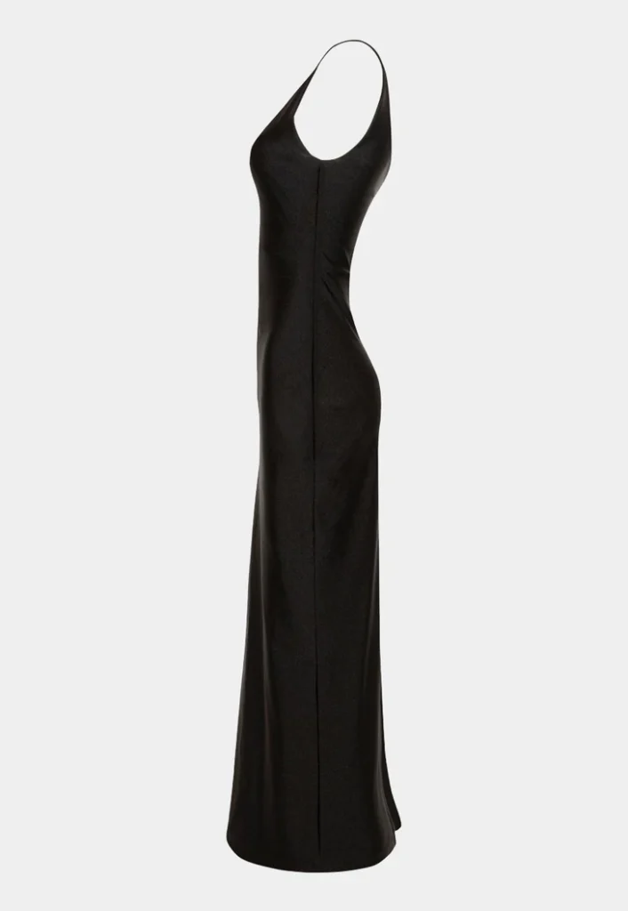 Vestido longo preto de modelagem ajustada, fotografado de perfil em fundo neutro, destacando a silhueta elegante.